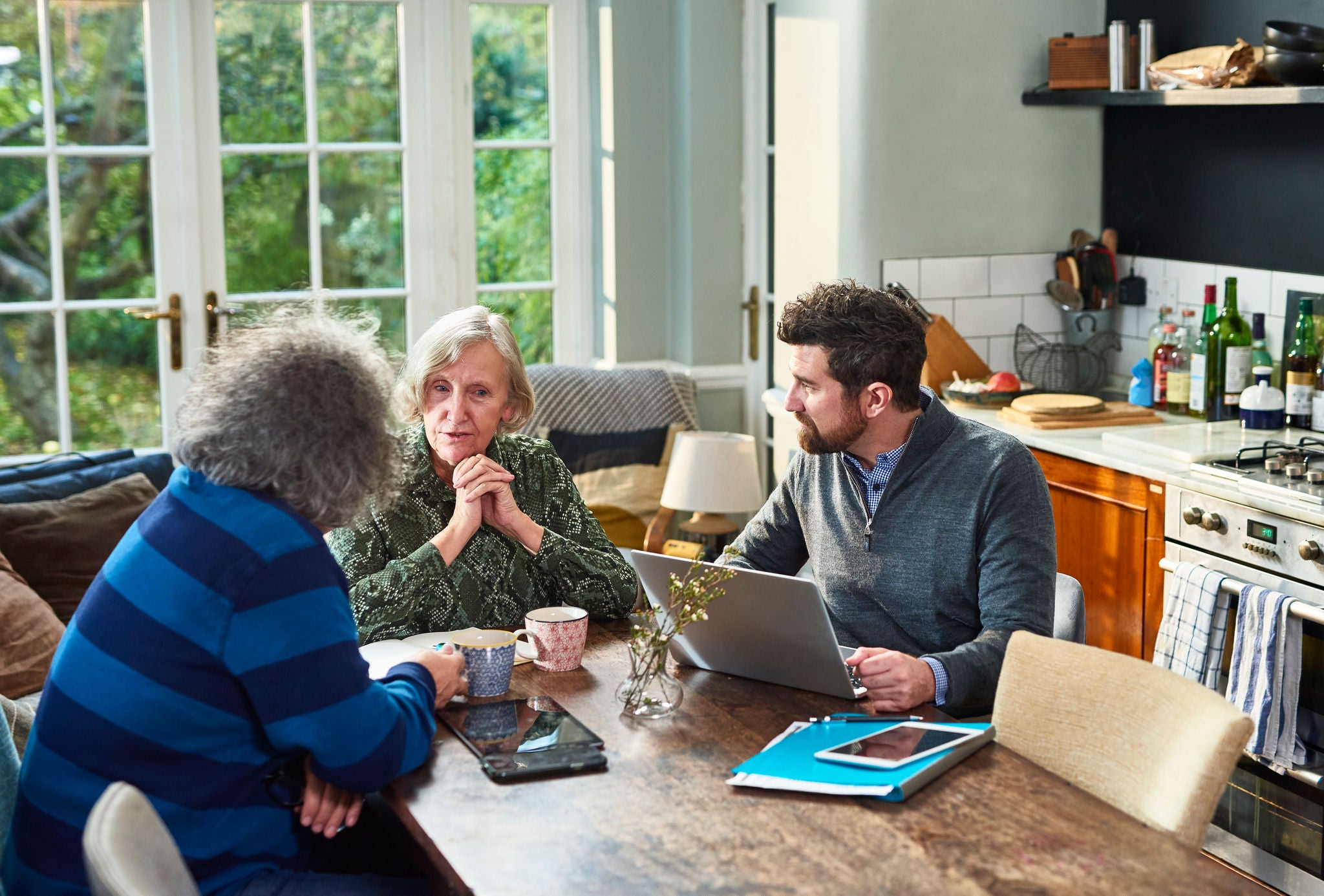 Financial advisor sitting at dining table with senior man and woman discussing financial plans