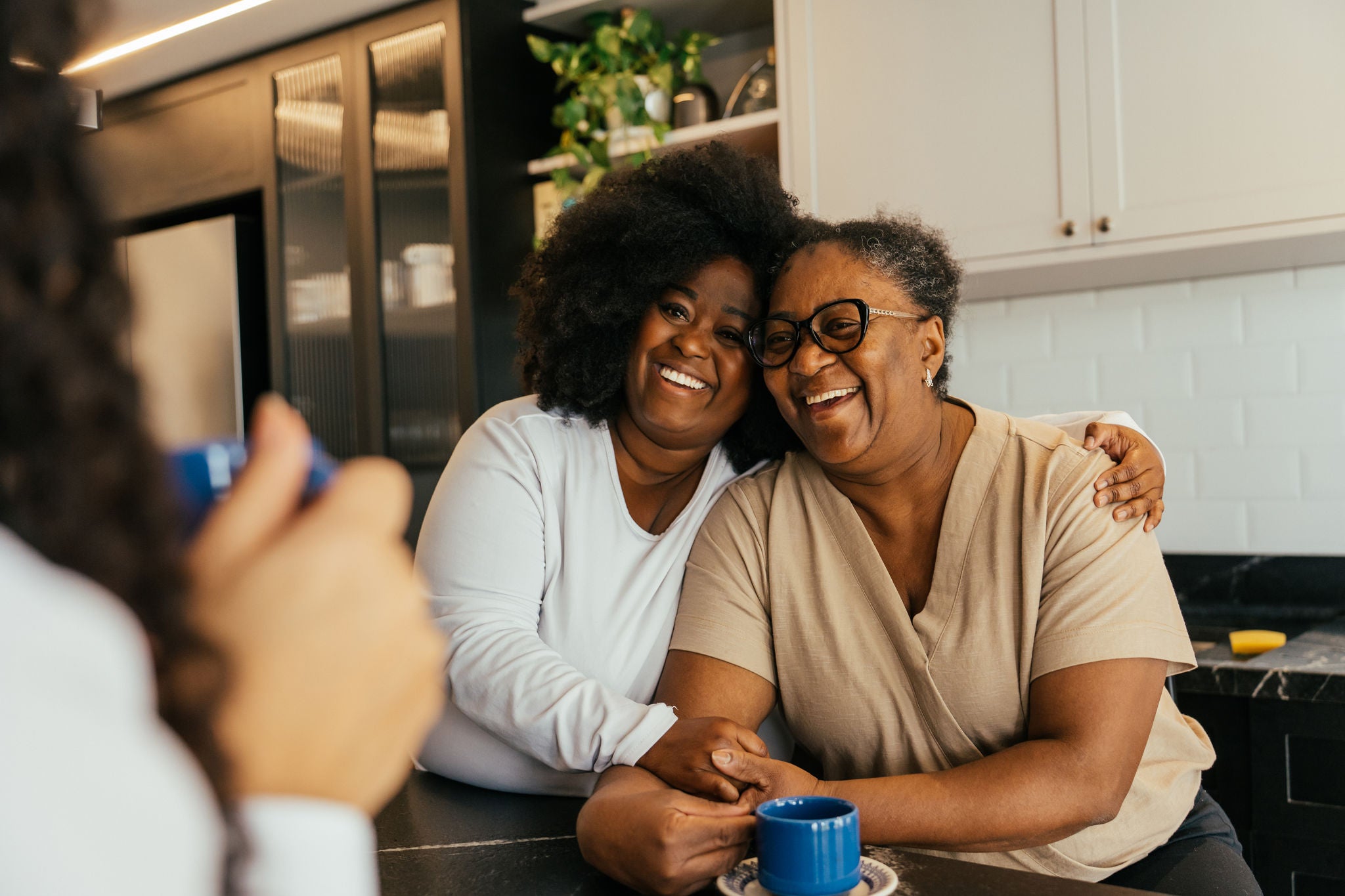 Adult daughter hugging her mother in the kitchen