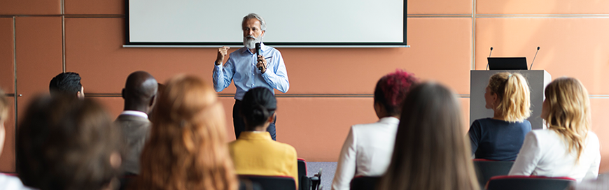 Man with microphone speaking to a class of adults